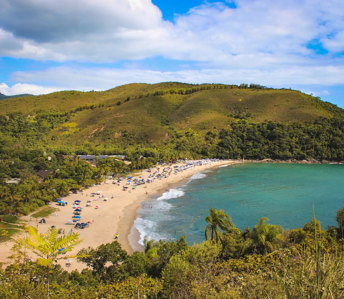 Playa de arena clara rodeada de cerros cubiertos de selva