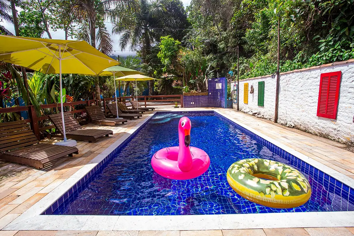 Piscina con flotadores de colores, sombrillas y jardín