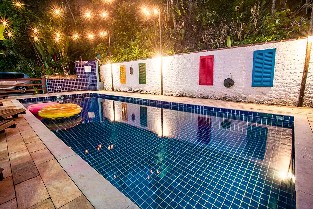 Pool lit up at night, with hanging lights and colorful windows