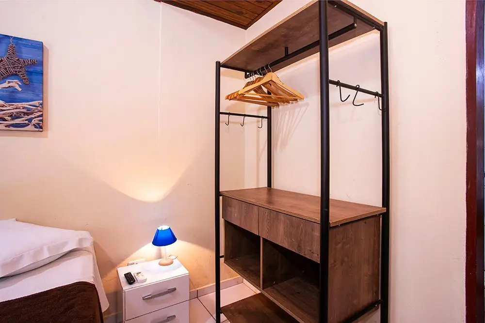 Clothes rack and nightstand with a lamp in the Economy Suite